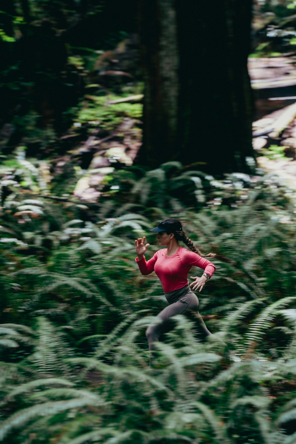 Woman trail running through a fern-lined forest